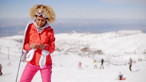 smiling skier check phone at top of slope