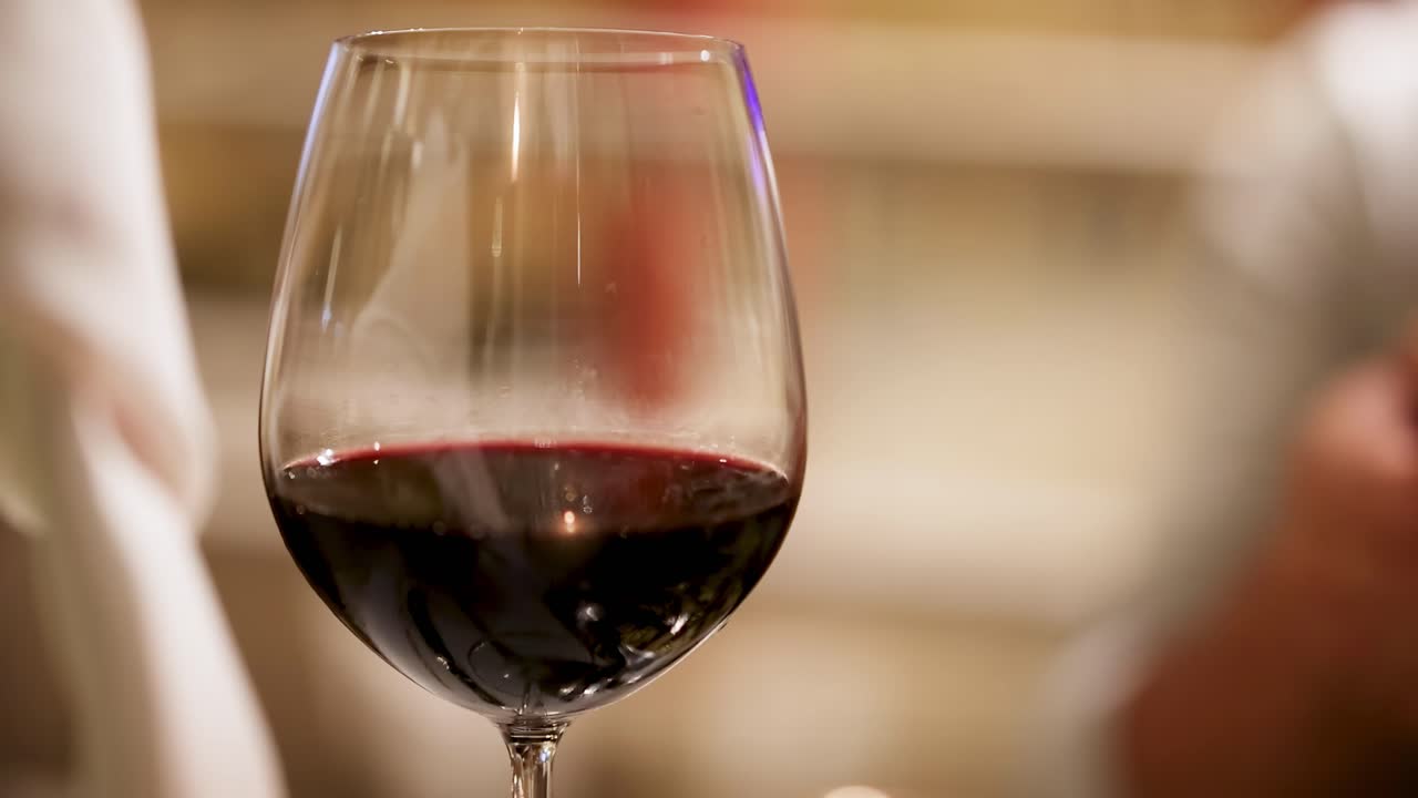 Una vista ravvicinata di un bicchiere pieno di vino rosso, che ne evidenzia il colore intenso e la limpidezza.