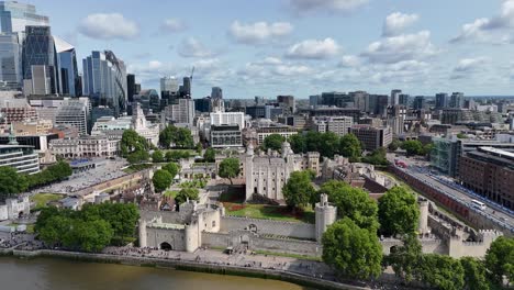 aerial pan of london’s iconic tower of london with striking contrast of historic architecture and modern city skyscrapers in the backdrop.