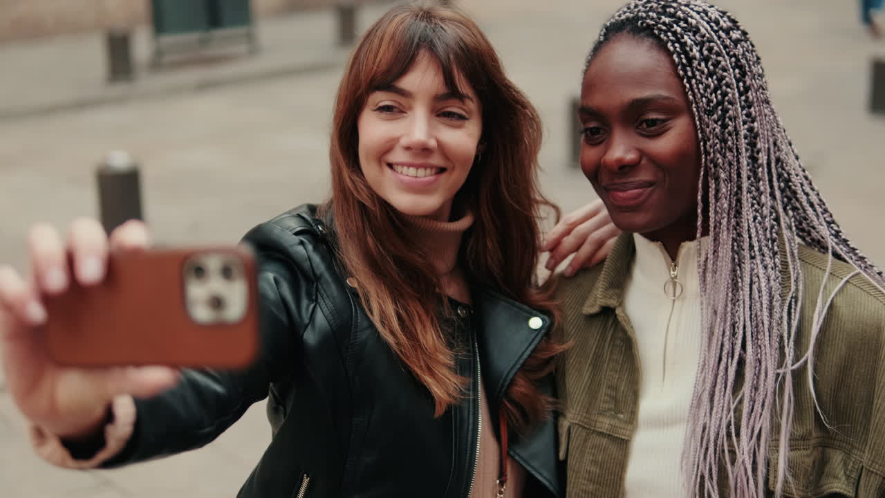 Due giovani donne felici e diverse che si fanno un selfie all'aperto