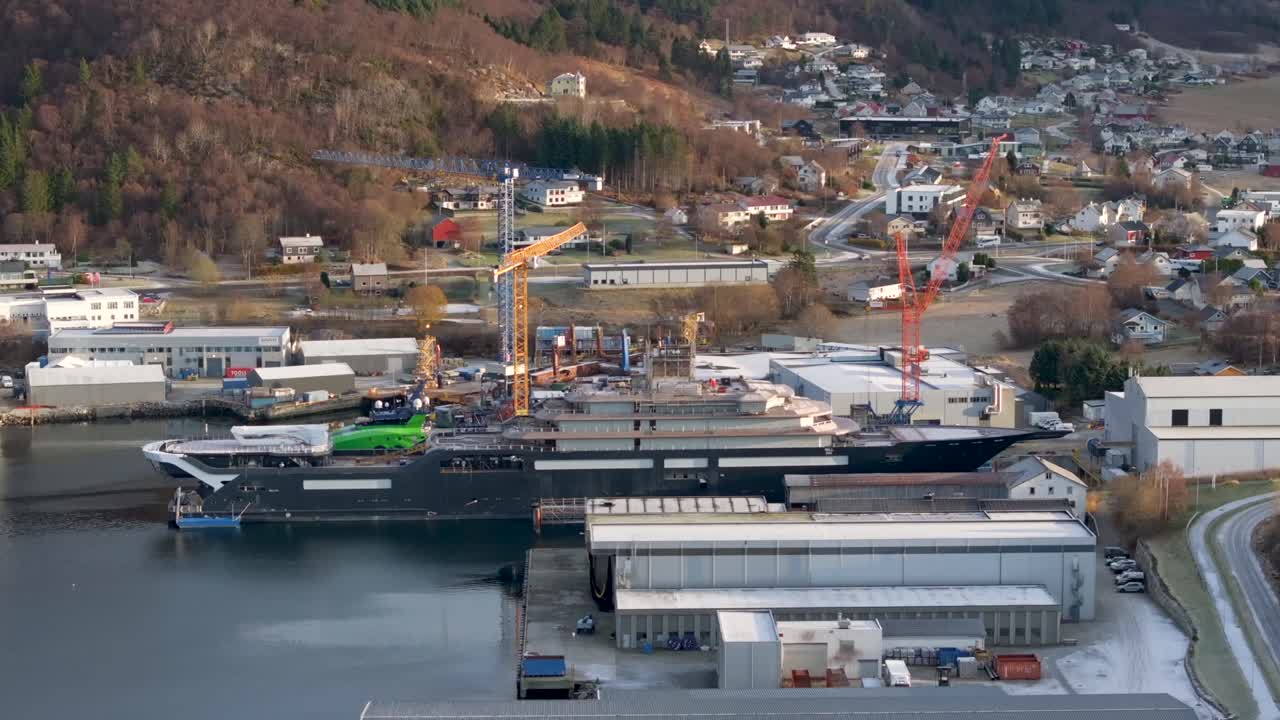 The drone flies up and forward and shows the entire long side of the research vessel "REV Ocean" docked at VARD shipyards in S&oslash;vik, Norway