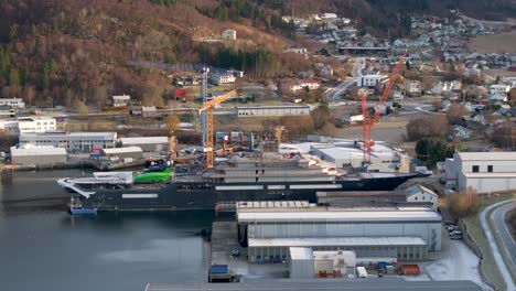 The-drone-flies-up-and-forward-and-shows-the-entire-long-side-of-the-research-vessel-"REV-Ocean"-docked-at-VARD-shipyards-in-Søvik,-Norway
