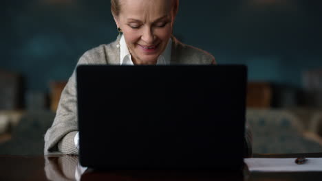 happy senior woman having video conference on laptop computer in classic interior