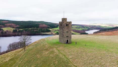 Old-derelict-castle,-monument,-disused-stone-tower,-with-people-walking-around-and-flying-a-drone