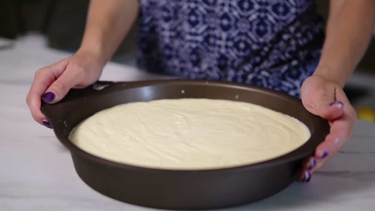 vista de cerca de las manos femeninas sacudiendo la sartén con queso crema blanco cubriendo la base de la galleta. pastel de queso