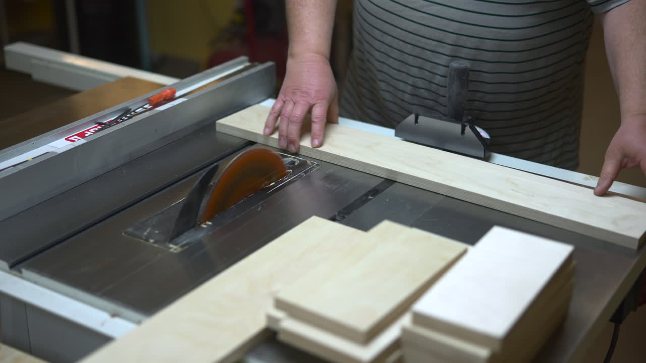 Falegname caucasico che taglia assi di legno con una sega circolare da banco, guida tagli longitudinali precisi vicino alla lama rotante, mani. Media