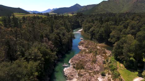 a turqoise blue river flowing through the lush green forest valleys of new zealand