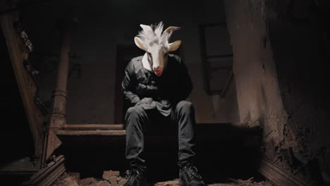 man in goat mask on abandoned stairs