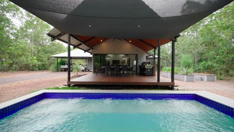 tropical villa-style home with a pool and patio, surrounded by lush greenery, offering a relaxing outdoor space. exterior of house home staged for real estate.