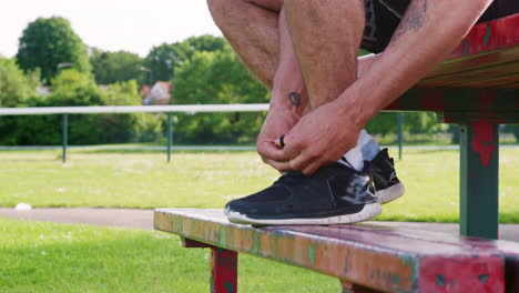 male runner tying shoelaces and starting run, low section