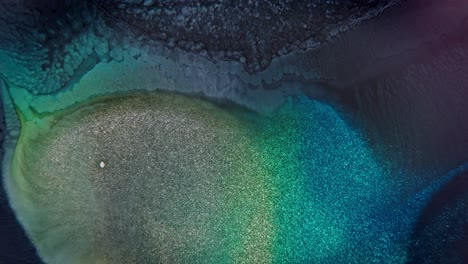 Close-up-of-blue-and-green-ink-granules-on-textured-surface-creating-a-sparkling,-underwater-like-abstract-effect