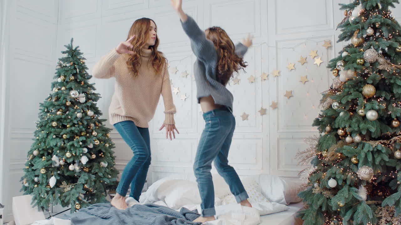 Happy mother and daughter making dance party on bed in private house.