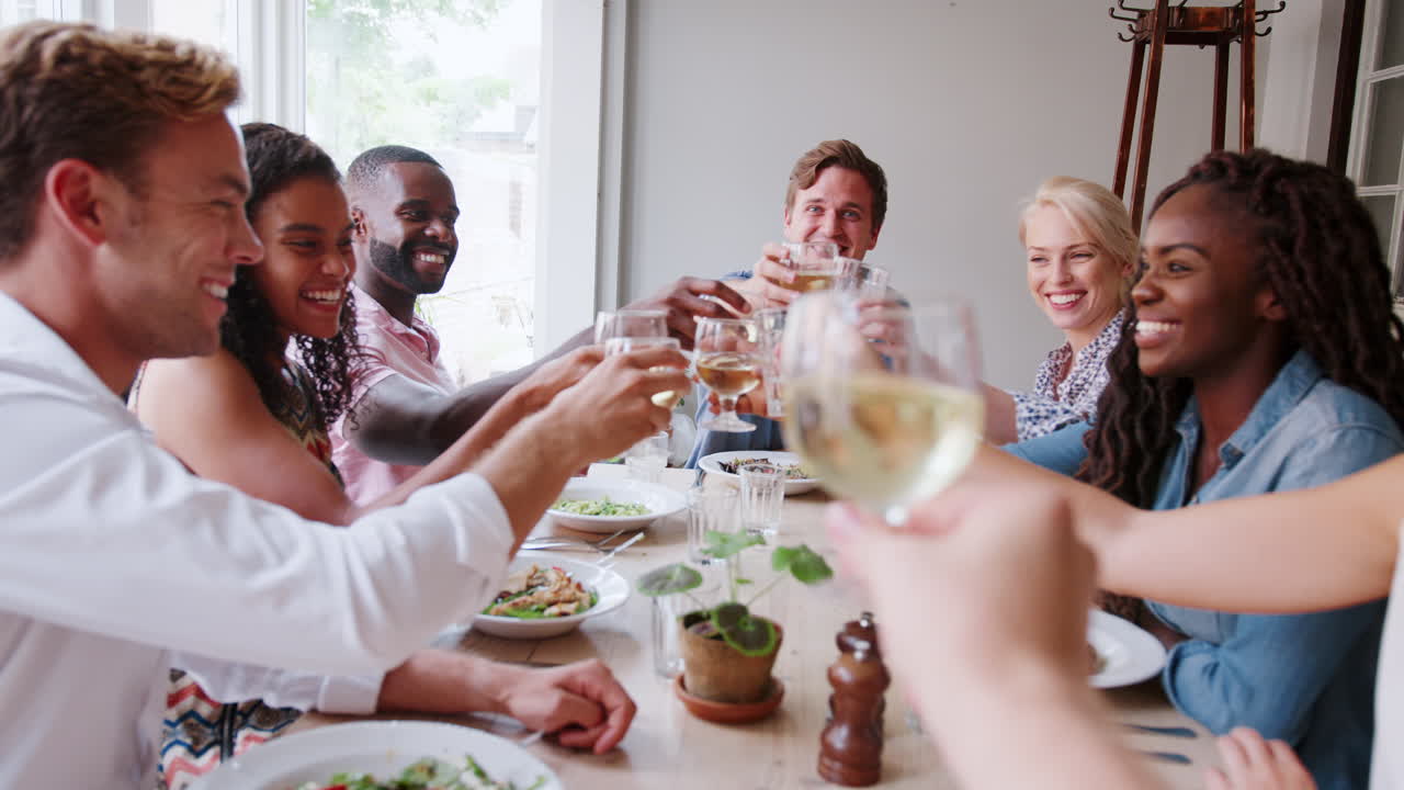 Groupe d'amis partageant un repas au restaurant et portant un toast à la caméra