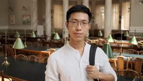 young asian male student smiling at camera in library