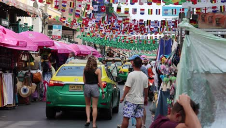 crowded market street with colorful decorations and taxi