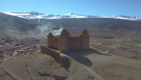 aerial view of the castle of la calahorra with sierra nevada behind in granada, spain