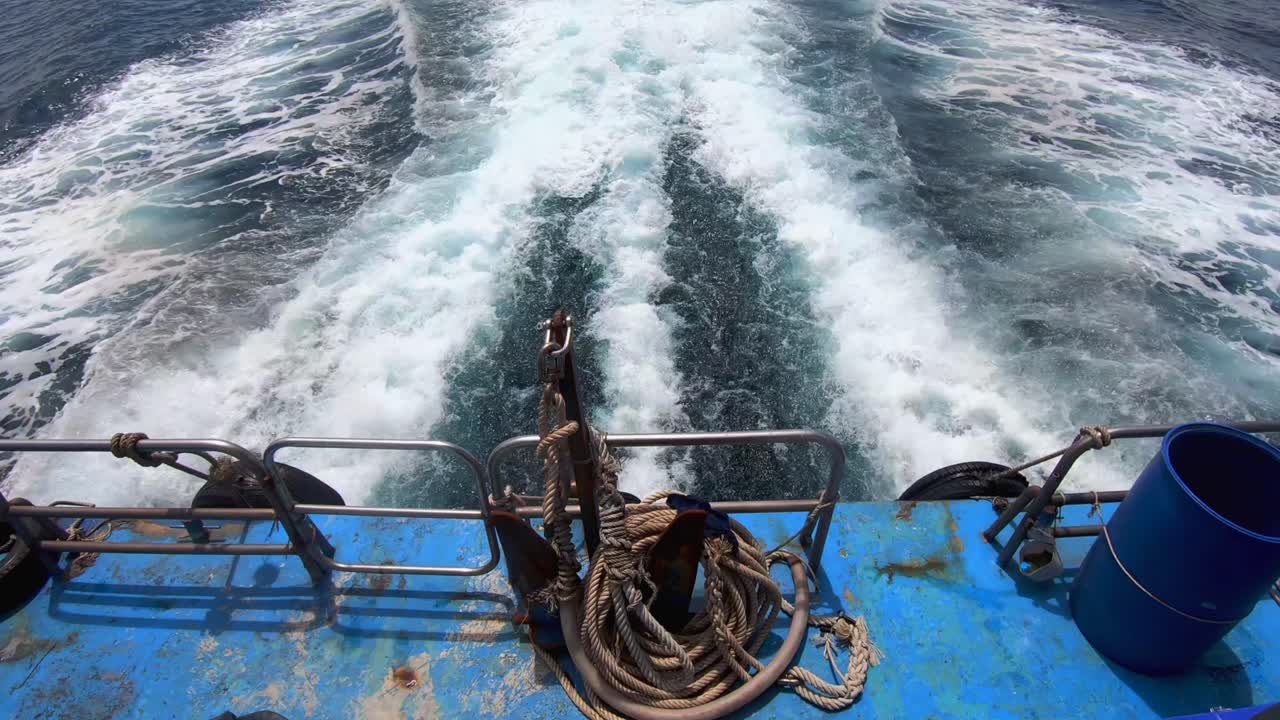 4k 29의 깊고 푸른 바다를 통해 엔진 동력에서 깨어나 앵커와 로프가 있는 보트 뒤에서 보기