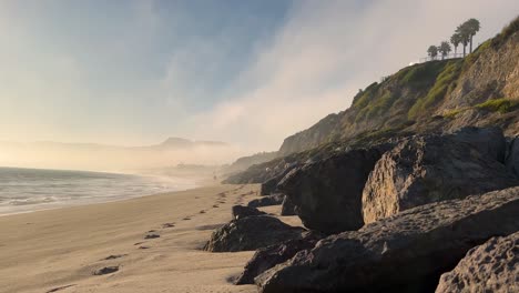 4k-Foggy-Malibu-Beach-Blue-and-Green-Ocean-waves-crash-into-the-rocky-shore-on-a-cloudy-day-b-roll