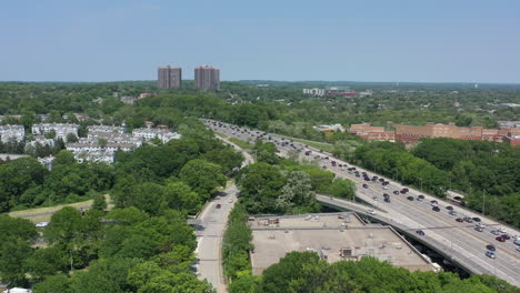 An-aerial-view-over-a-busy-parkway-next-to-a-large-park-with-green-trees
