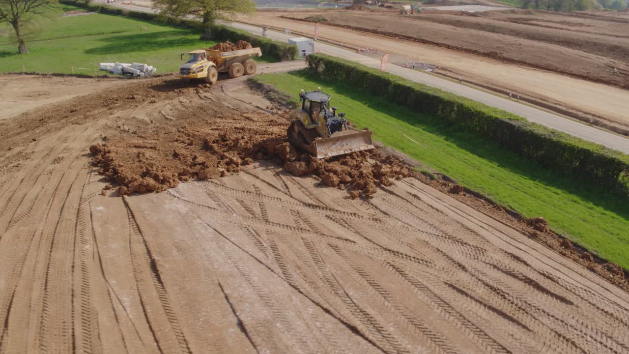 A bulldozer works on flattening out earth on a large construction site