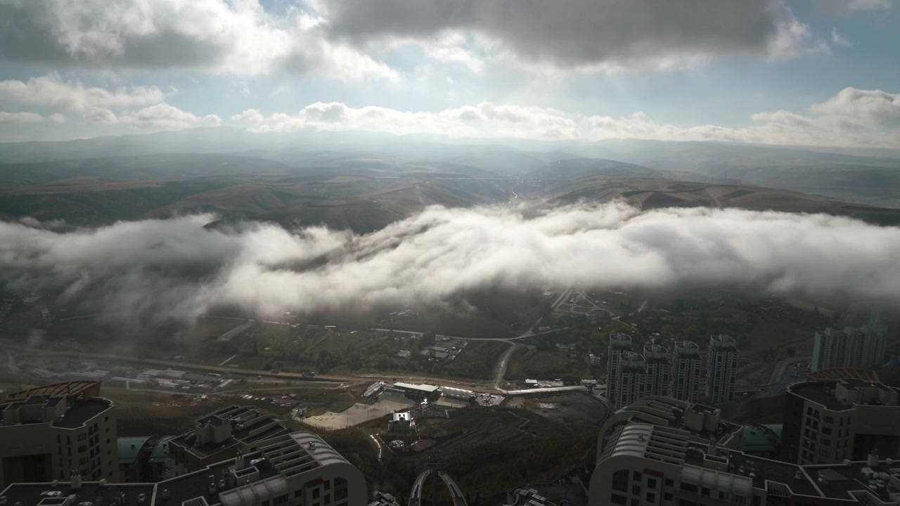 Aerial View of Low Clouds Moving Over City and Hills
