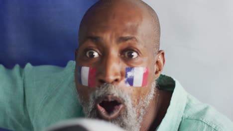 Video-of-happy-african-american-man-with-flags-watching-match-in-tv