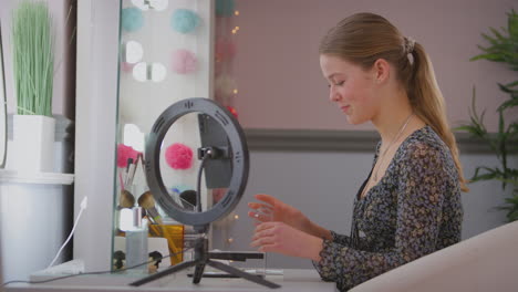 chica adolescente en el dormitorio grabando en línea tutorial de maquillaje en teléfono móvil - filmado en cámara lenta