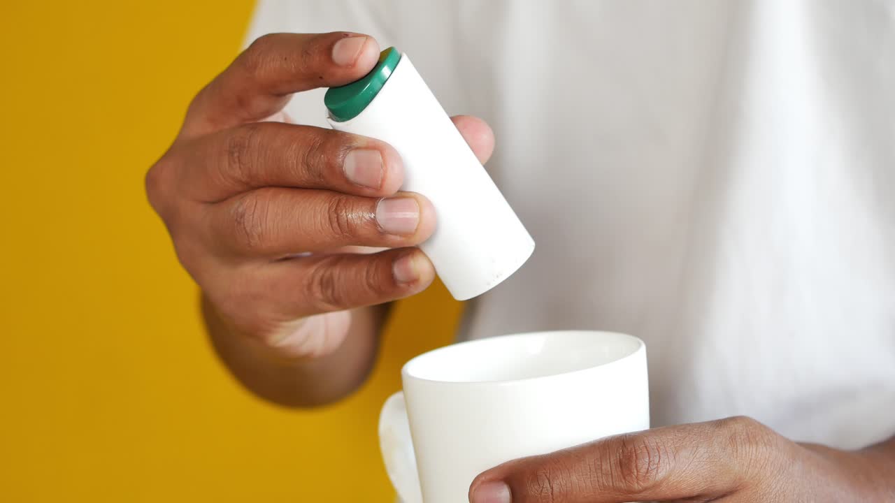 joven poniendo edulcorante artificial en el té