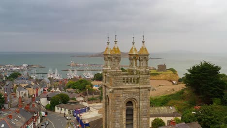 aerial dolly to gilded gold spires on tower of church of the assumption in howth north dublin ireland with ireland's eye off coast