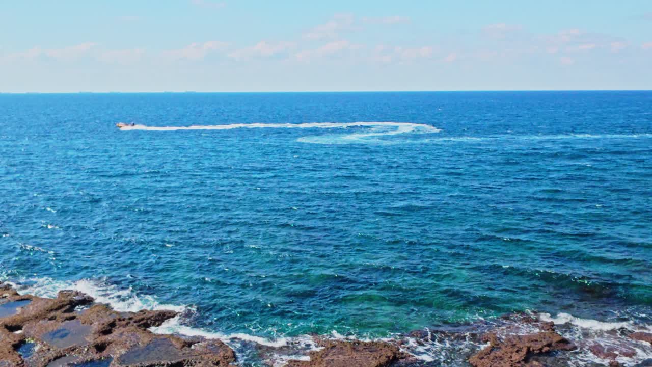 Motorboat turning on sea with rocky coast akko israel