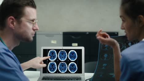 vista posterior de dos médicos caucásicos discutiendo sobre la exploración médica de rayos x a bordo y la computadora