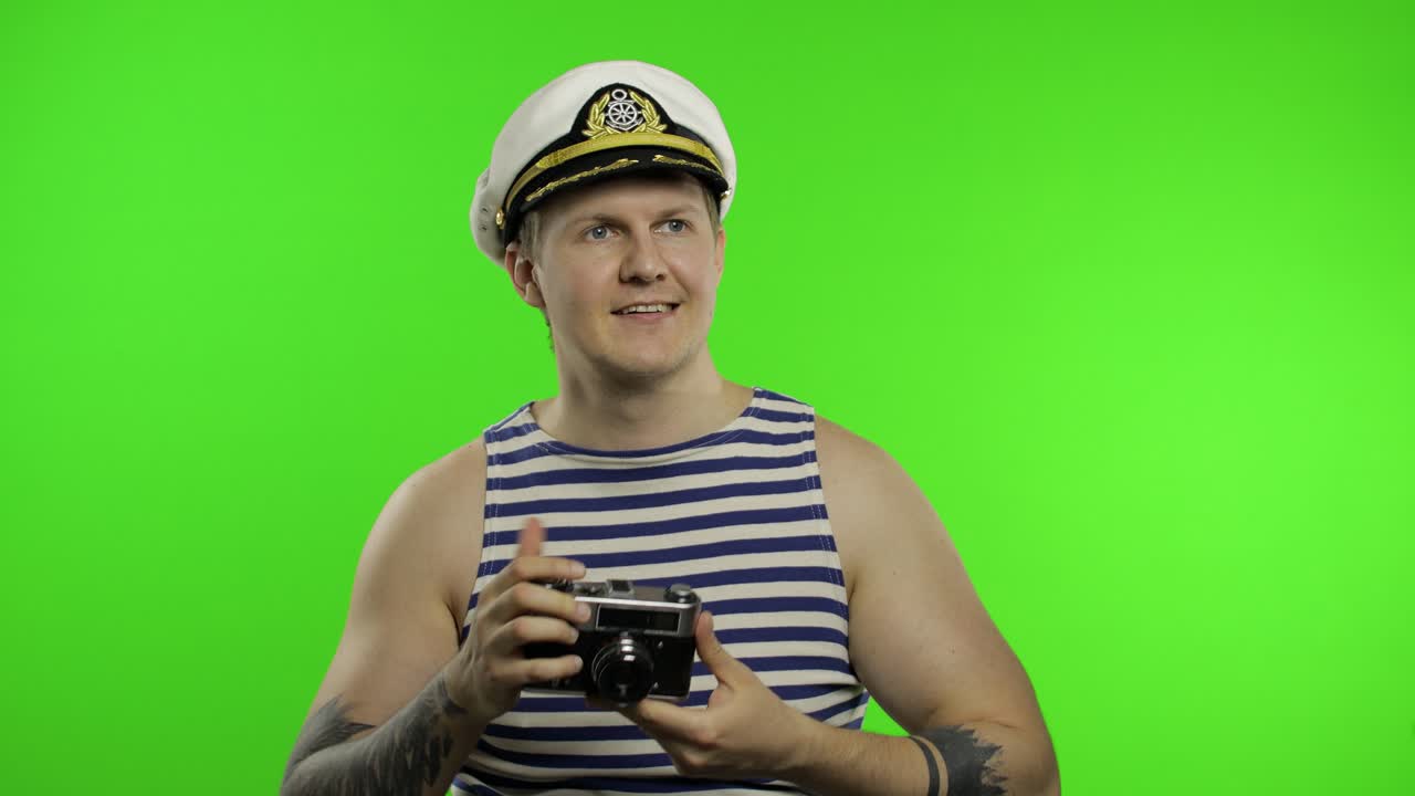un joven marinero toma una foto con una cámara retro. un marinero en chaleco de marinero