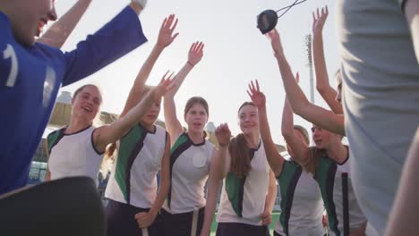 female hockey players forming hand stack on the field