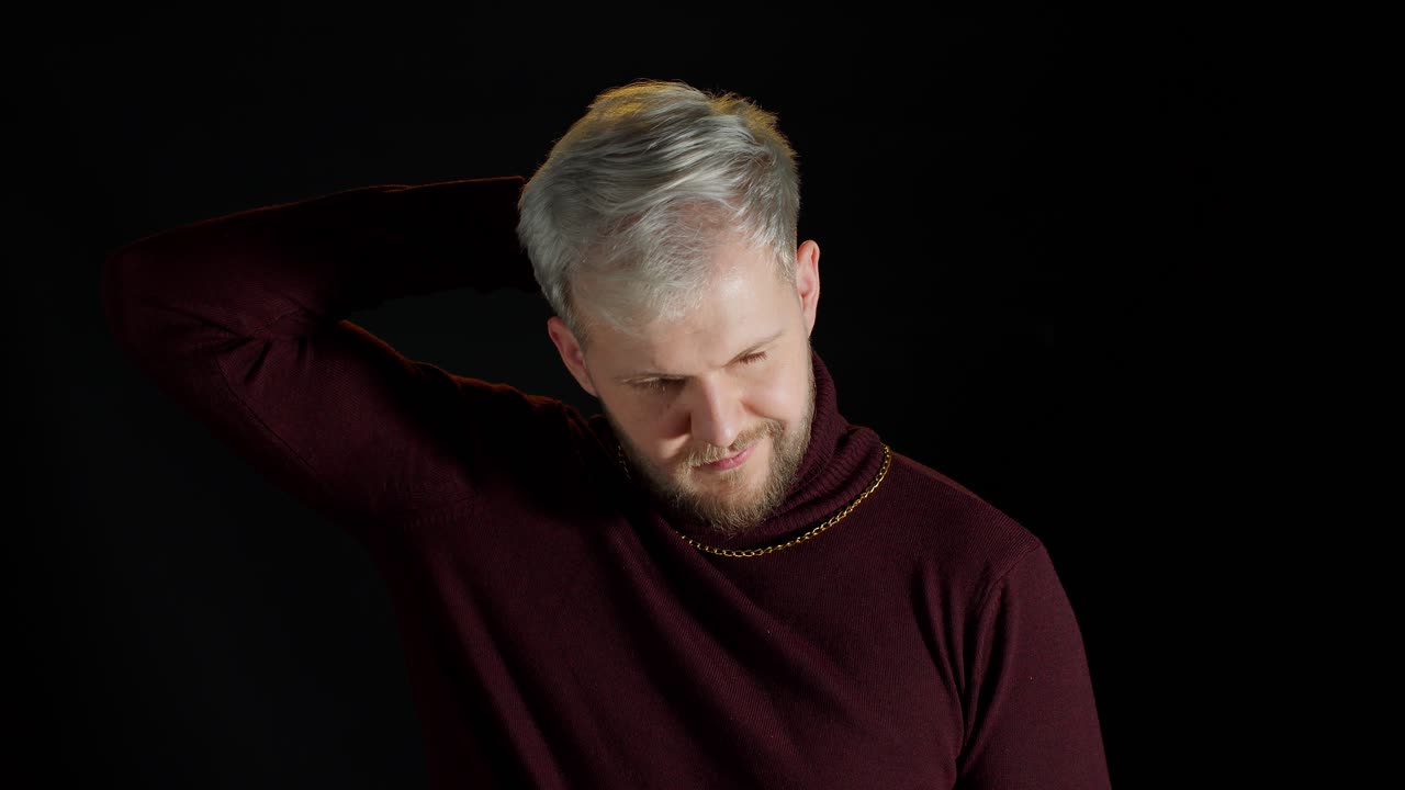 트렌디 한 스타일리시 옷 을 입은 웃는 즐거운 젊은 남자 가 머리 위 에 손 을 고 카메라 를 바라보고 있다