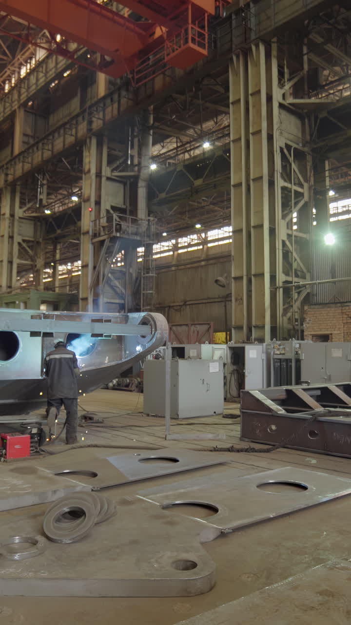 Workers performing welding in a large industrial factory