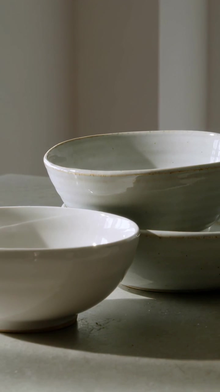 Vertical video: Shifting soft light and tiny camera framing showing rims on glazed bowls on table