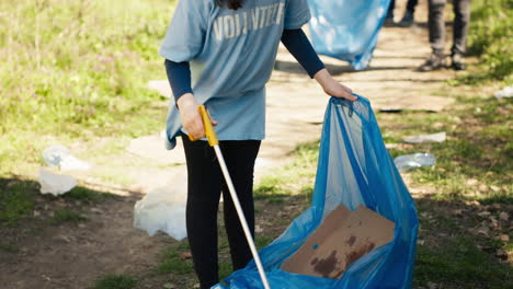 niño pequeño usando una herramienta de pinzas para agarrar y recoger la basura del bosque