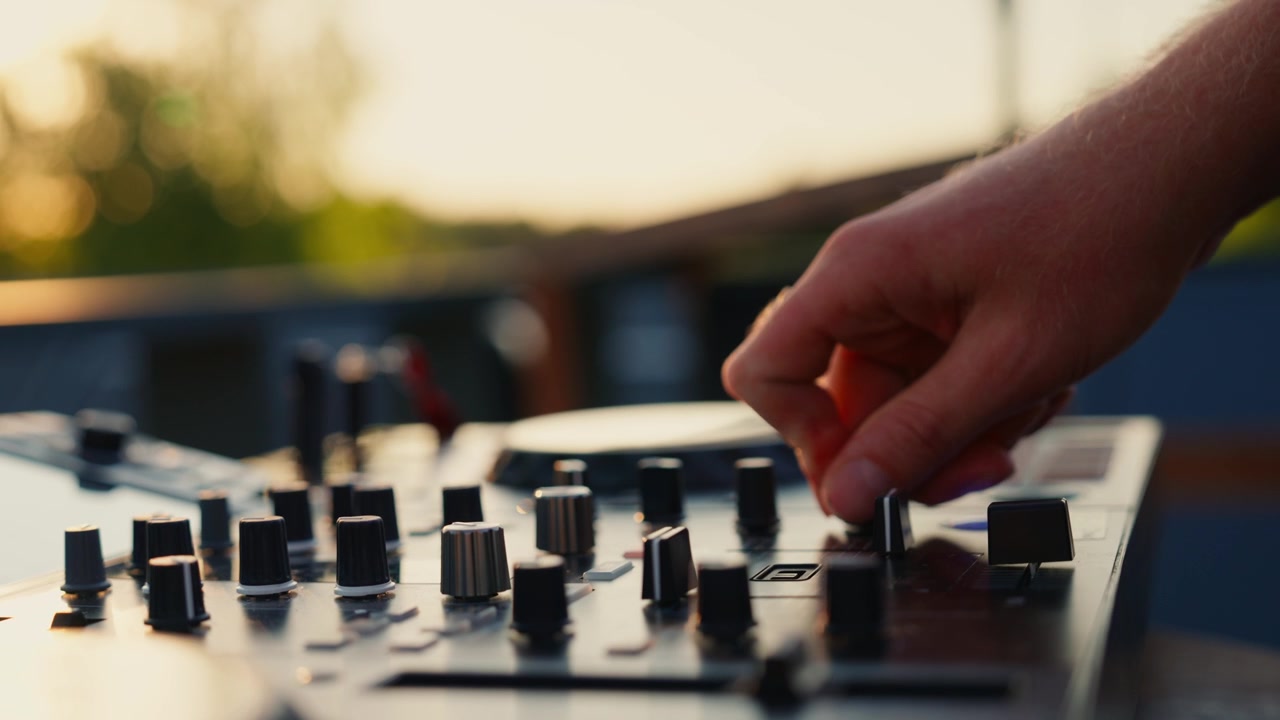 DJ che regola le manopole del mixer audio al tramonto