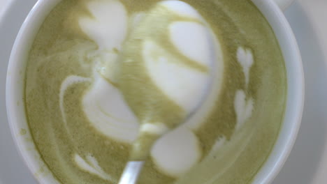 un primer plano del barista terminando la imagen de la crema en el latte matcha