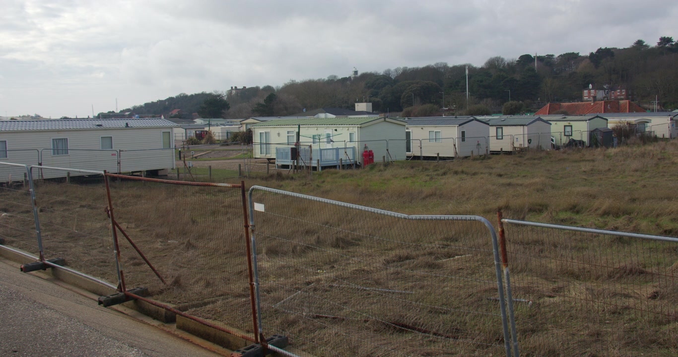 Vidvinkelbilde av en nedslitt campingvognpark ved siden av industribygg og ødemark ved Lowestoft Denes