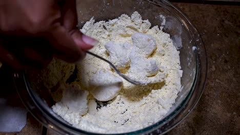 overhead view of breading cauliflower in bowl of flour, slow motion