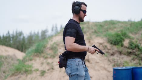 masculine shooting instructor at firing range insert magazine into handgun