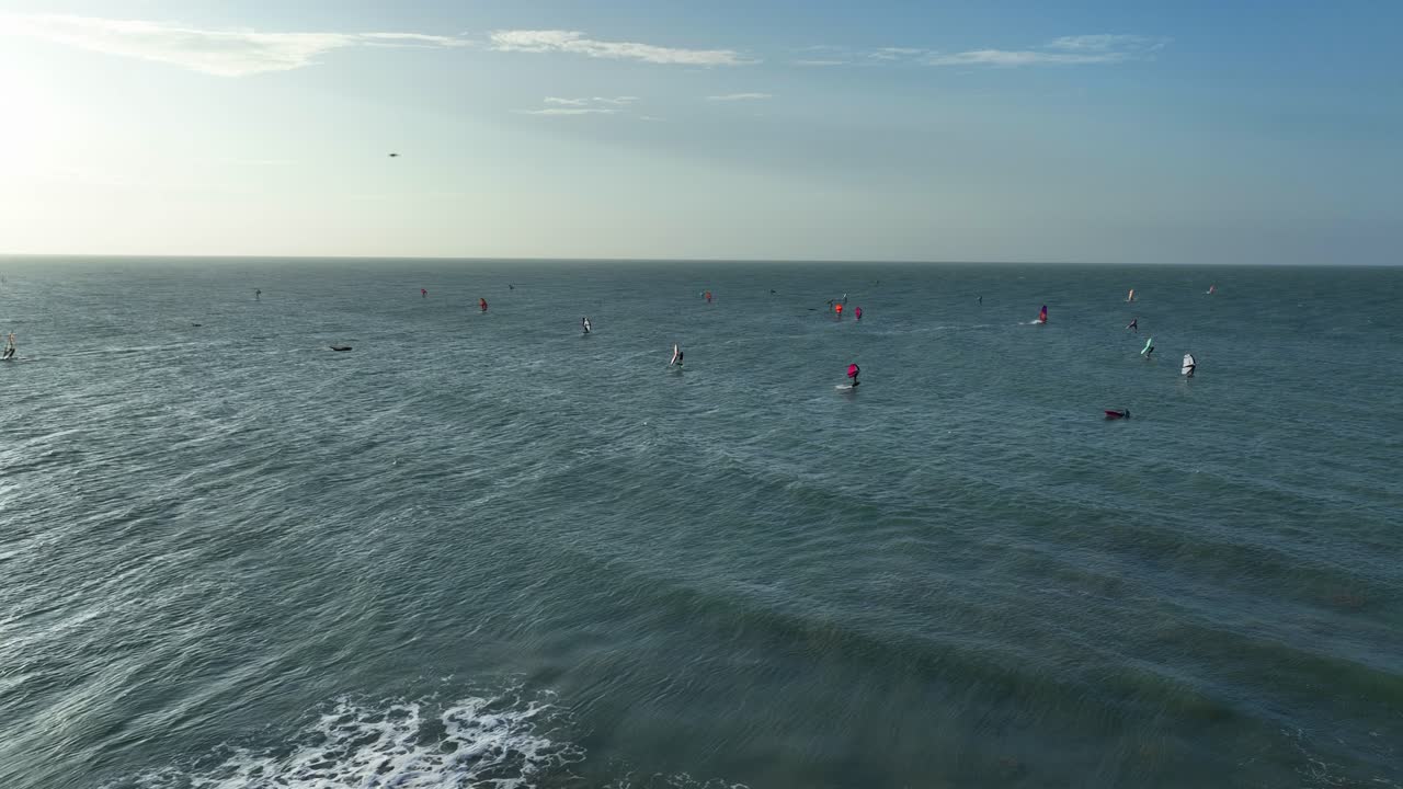 Aerial: windsurfers on Atlantic Ocean next to Jericoacoara Beach during the day in Jijoca de Jericoacoara, Ceara, Brazil, pan drone shot