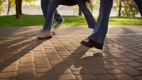 legs walking paving street close up. family enjoying warn sunny evening in park.