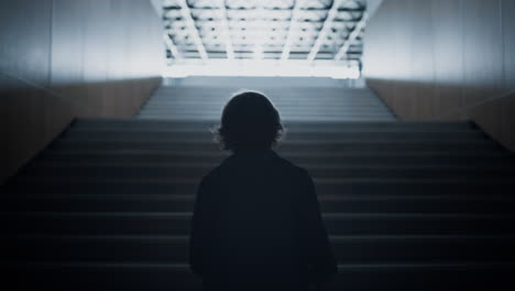 Teenager-silhouette-going-upstairs-alone-on-light.-Teen-student-walk-stairway.