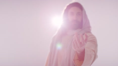 fotografía retroiluminada de un hombre con cabello largo y barba que representa la figura de jesucristo extendiendo la mano en amistad hacia la cámara 2