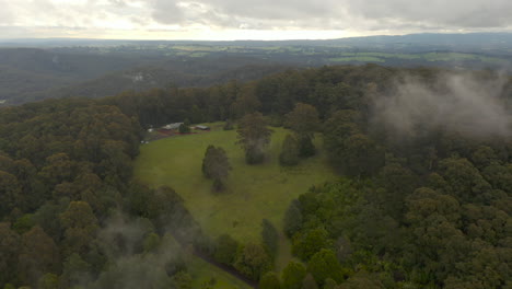 smooth aerial decent looking down towards isolated house within lush natural landscape