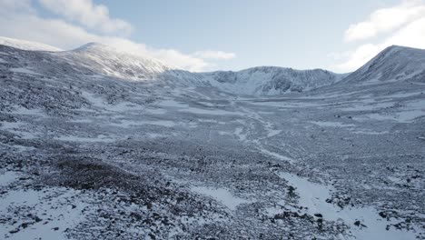 Imágenes-Aéreas-De-Drones-Revirtiendo-Coire-An-T-sneachda-En-El-Parque-Nacional-De-Cairngorms-Para-Revelar-La-Montaña-Cairngorm-En-Escocia-Con-Montañas-Cubiertas-De-Nieve-Y-Páramos-En-Un-Paisaje-Invernal