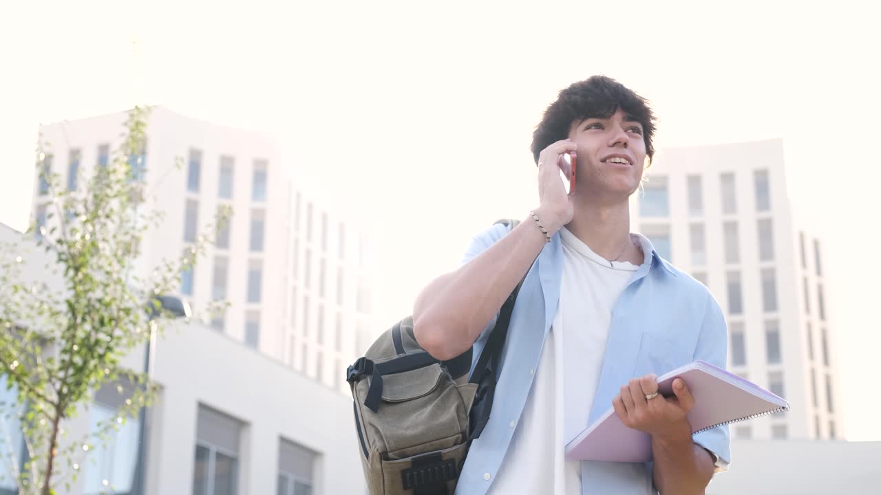 Smiling male student chatting on cellphone on university campus