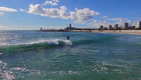 slow motion (120fps): wide shot of male surfer surfing the wave in barcelona, spain